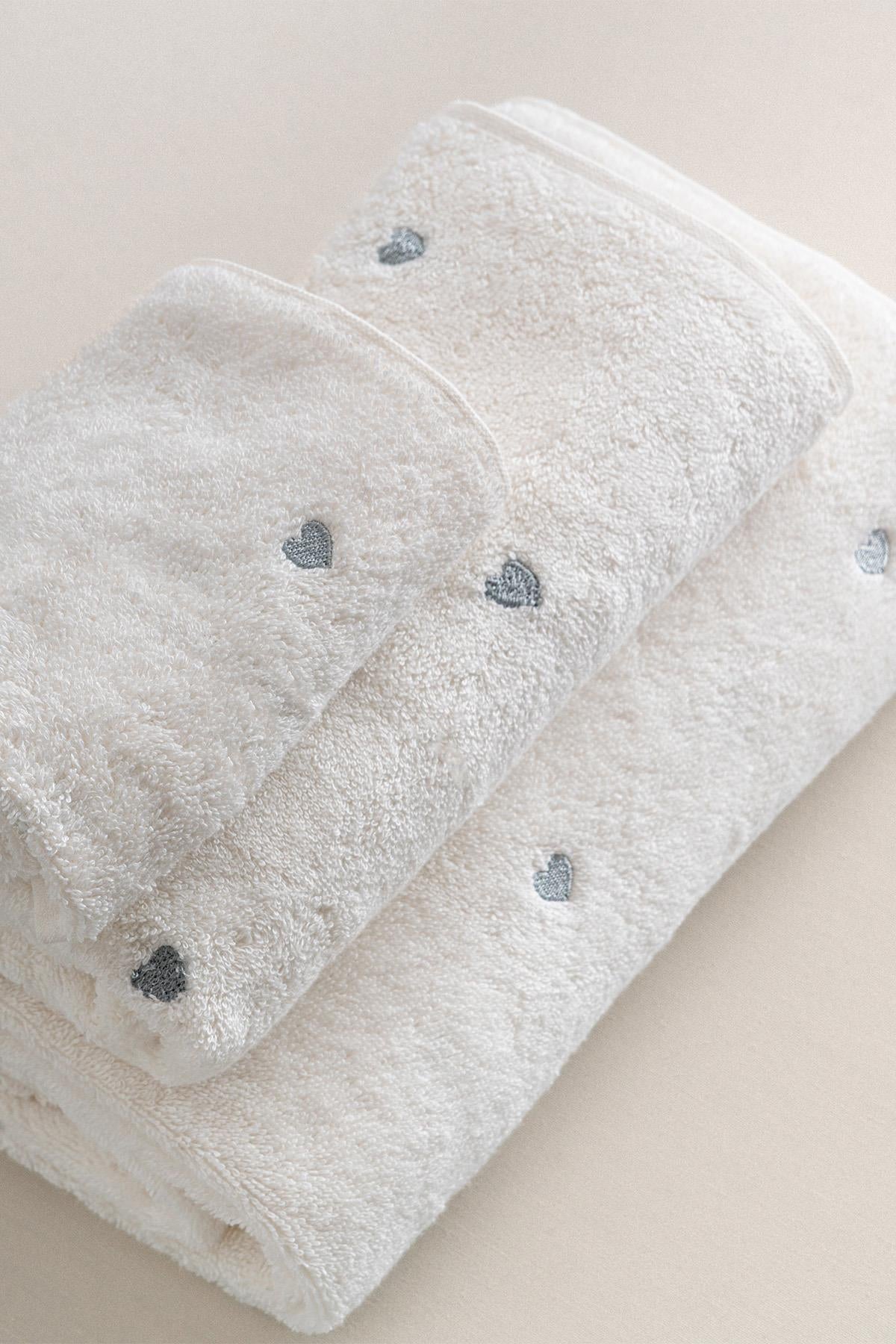 Juego de toallas blanco con detalle de corazón plateado, textura suave, accesorio de baño cómodo