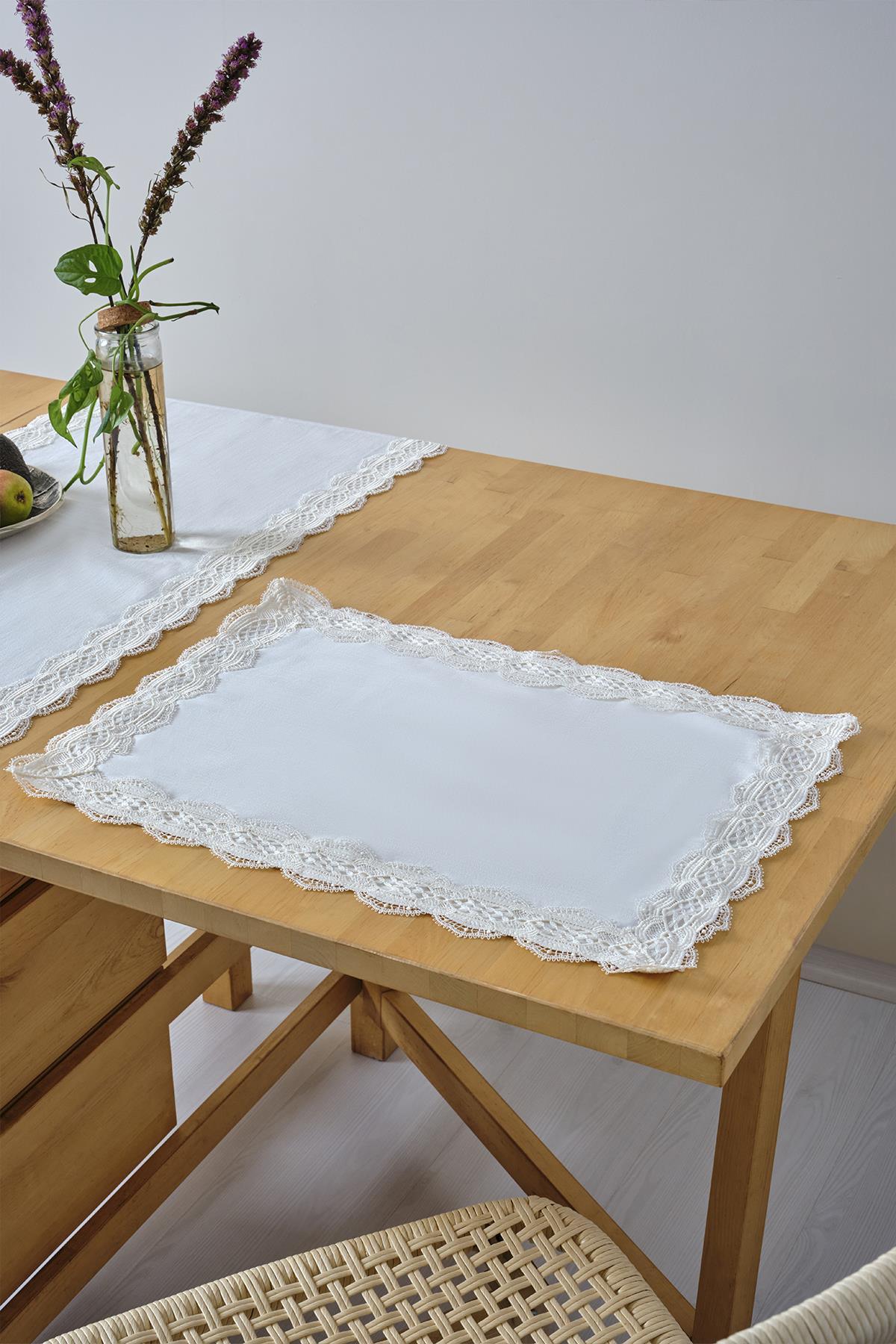 Individual de mesa blanco con borde de encaje sobre una mesa de madera, decoración de mesa elegante