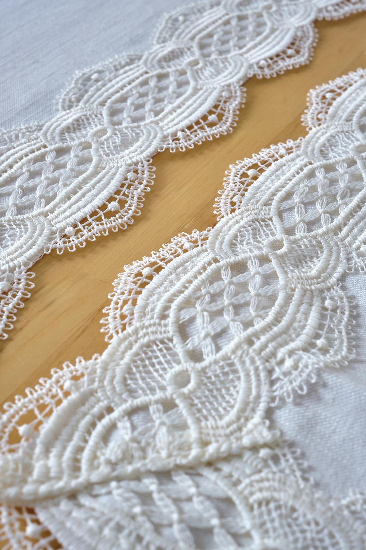 Individual de mesa blanco con detalles de encaje extendido sobre un mantel