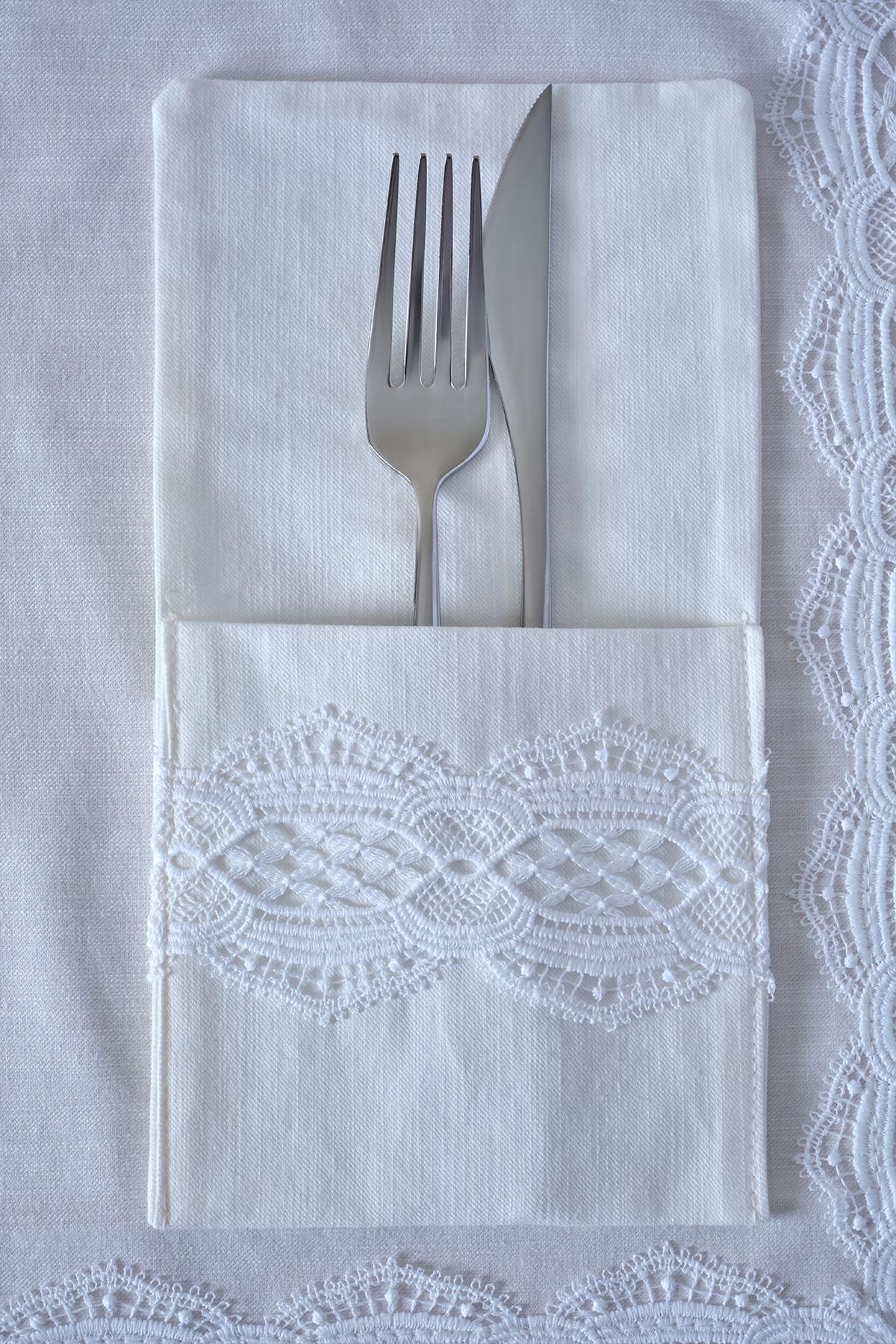 Cuchillo y tenedor sobre una servilleta blanca con detalles de encaje, elegante presentación de mesa