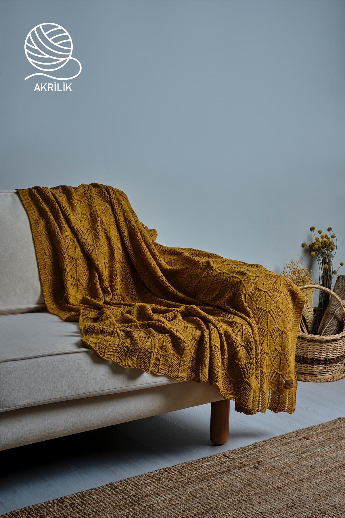 Manta de TV de punto grueso en color amarillo, dispuesta de forma decorativa sobre un sofá