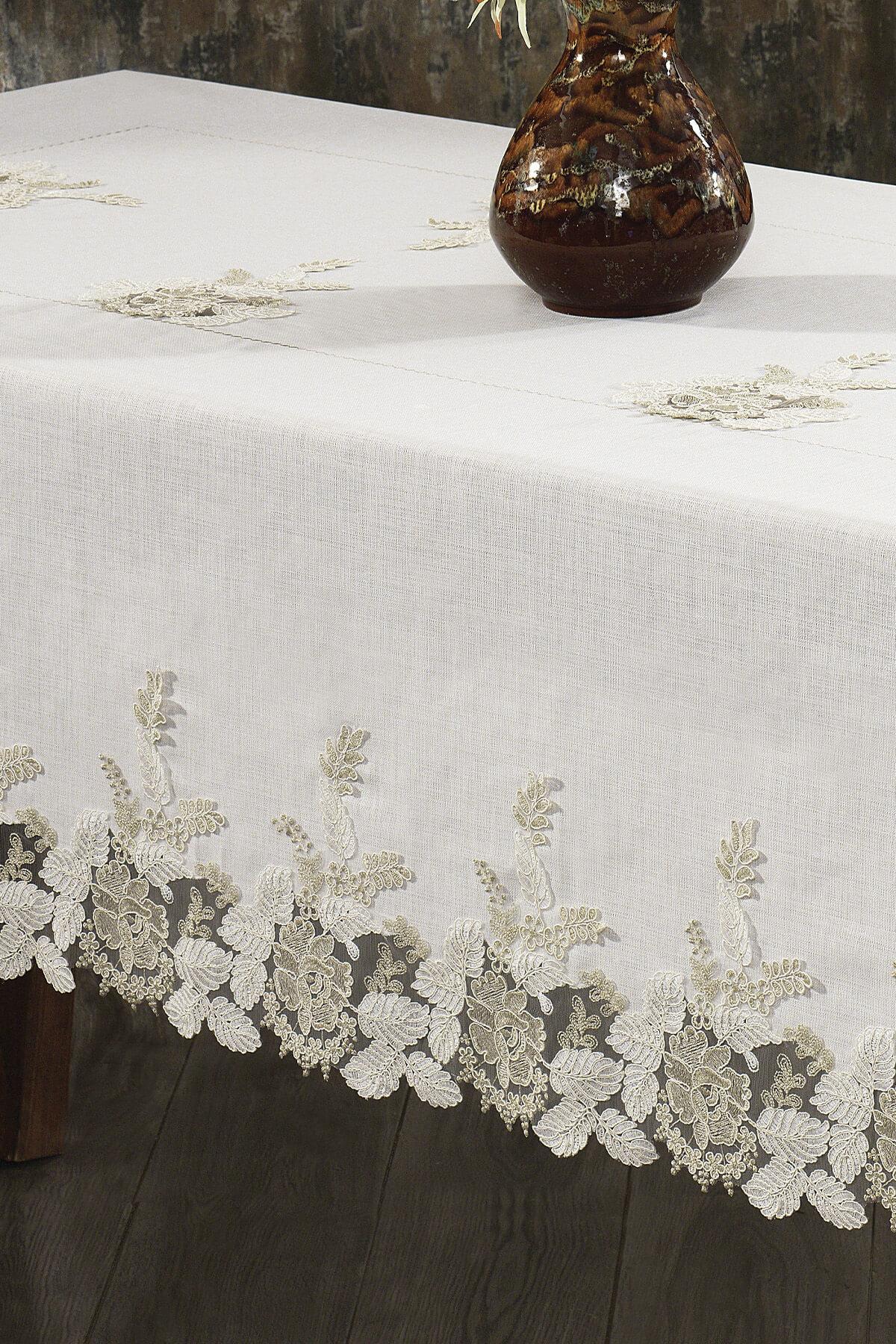 Mantel de encaje color crema, antimanchas, junto a una mesa elegante y un jarrón de cerámica.