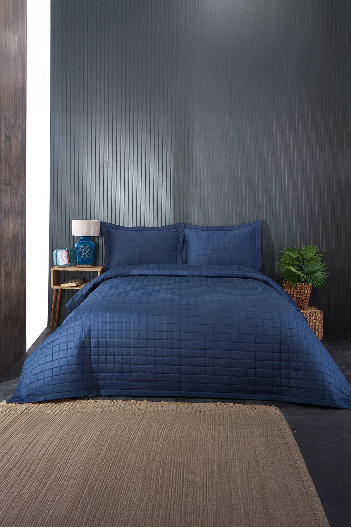 Juego de colcha y fundas de almohada matrimonial capitoné en azul marino en un dormitorio moderno