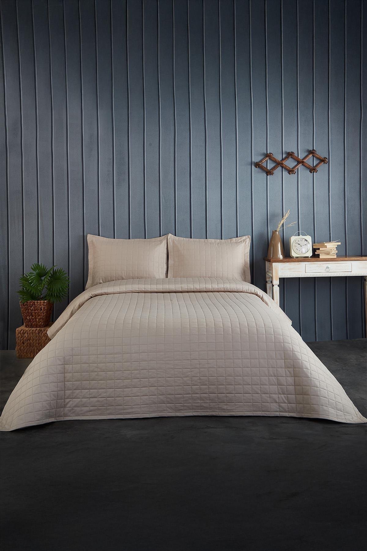 Colcha doble acolchada en un dormitorio moderno, color beige, con almohadas