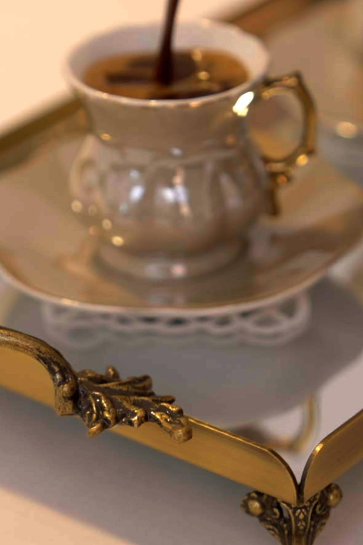 Presentación de café en taza de porcelana sobre bandeja pequeña con asas en color oro envejecido