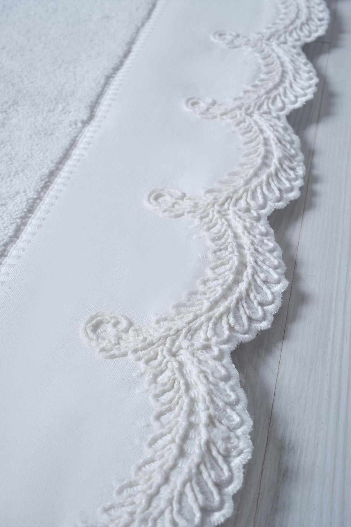 Primer plano de una alfombra de baño de algodón blanco con detalles de encaje