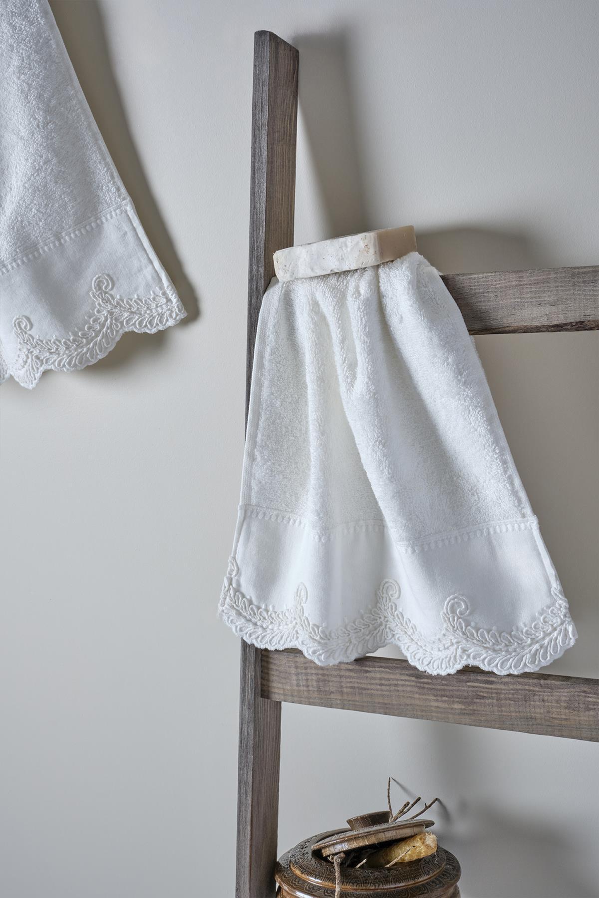 Toalla de cuerpo blanca con bordado de encaje, sobre una escalera de madera, con detalles de bordes de diseño elegante