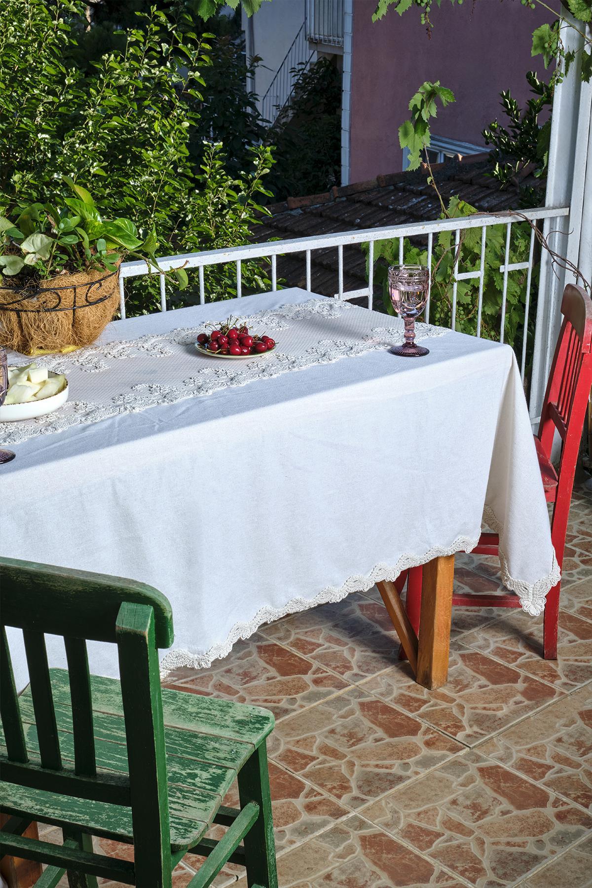 Mesa de balcón con mantel blanco de encaje, acompañada de sillas roja y verde