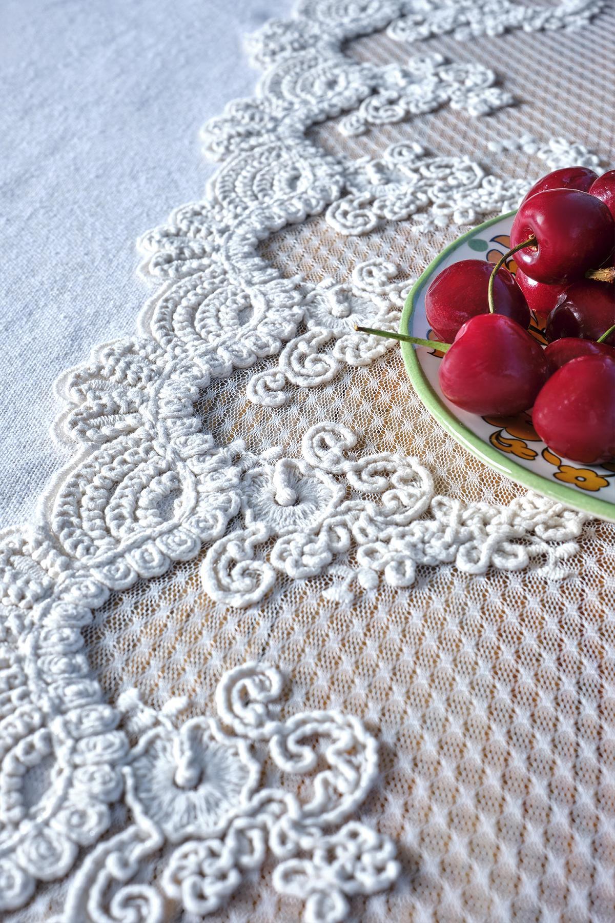 Mantel de mesa blanco con bordados de encaje, primer plano con cerezas en un plato sobre él