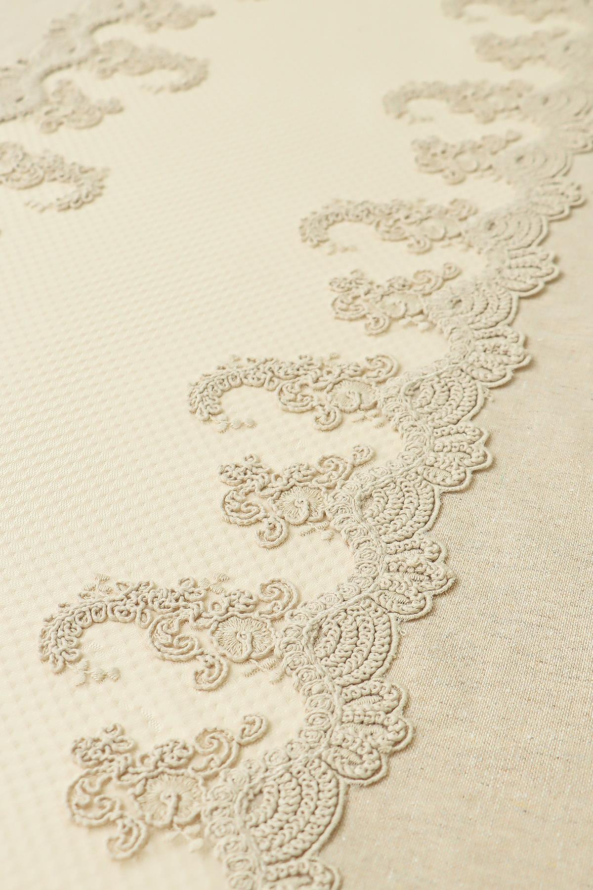 Mantel de color crema con detalles de encaje, diseño elegante y tejido texturizado.