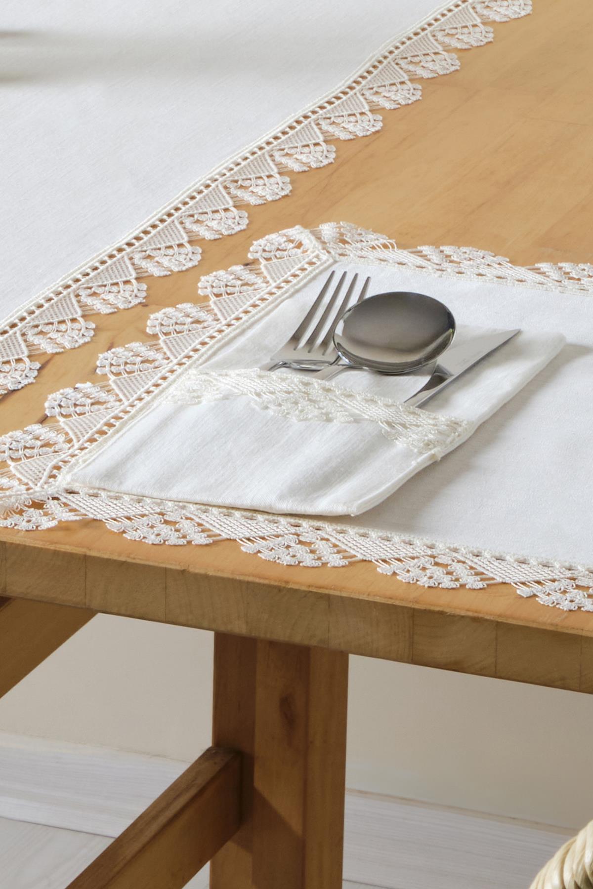 Mantel de encaje y juego de servilletas blancas con cubiertos sobre una mesa de madera
