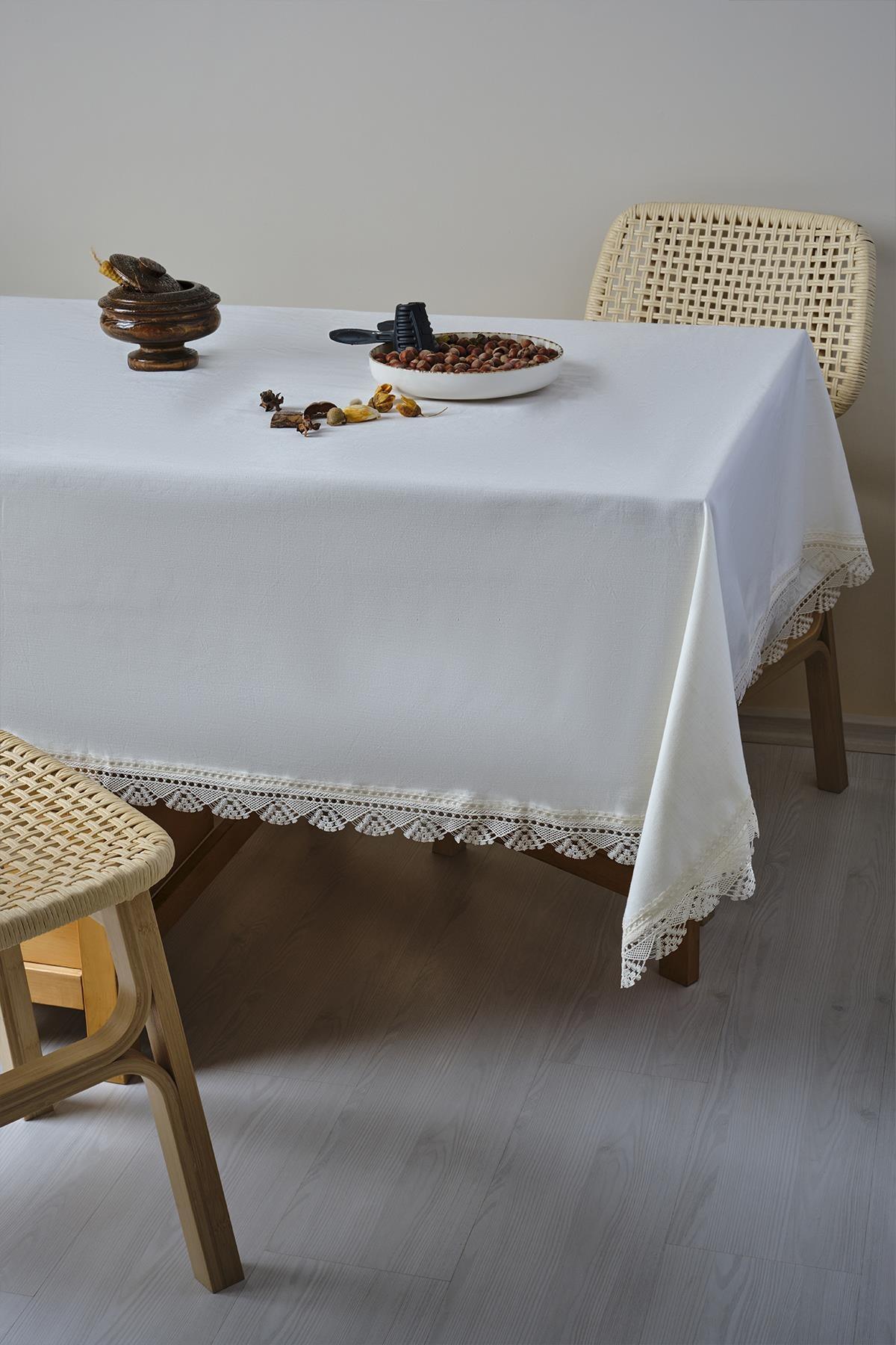 Mantel de mesa blanco con encaje y antimanchas sobre una mesa y sillas de madera modernas