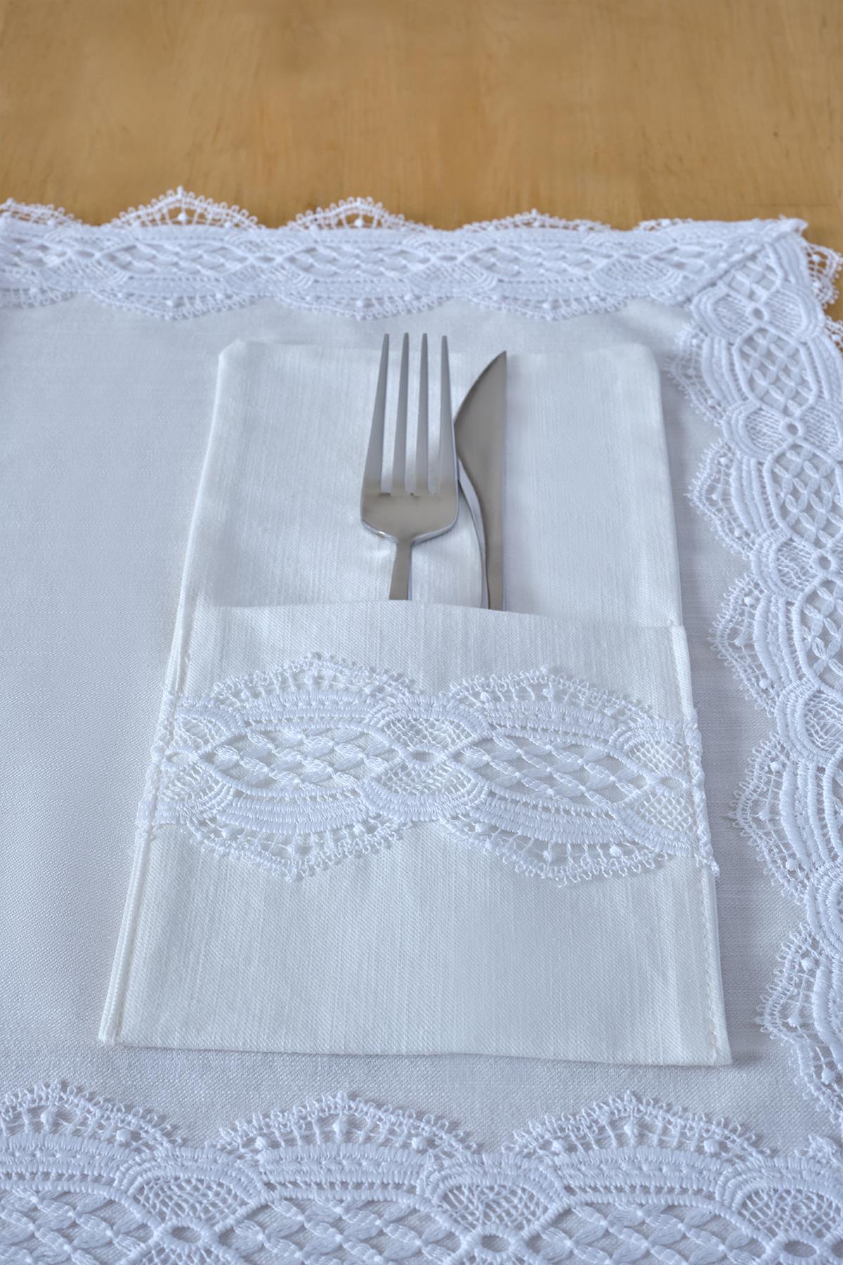 Servilletero de tela blanca con bordado de encaje, con tenedor y cuchillo sobre la mesa