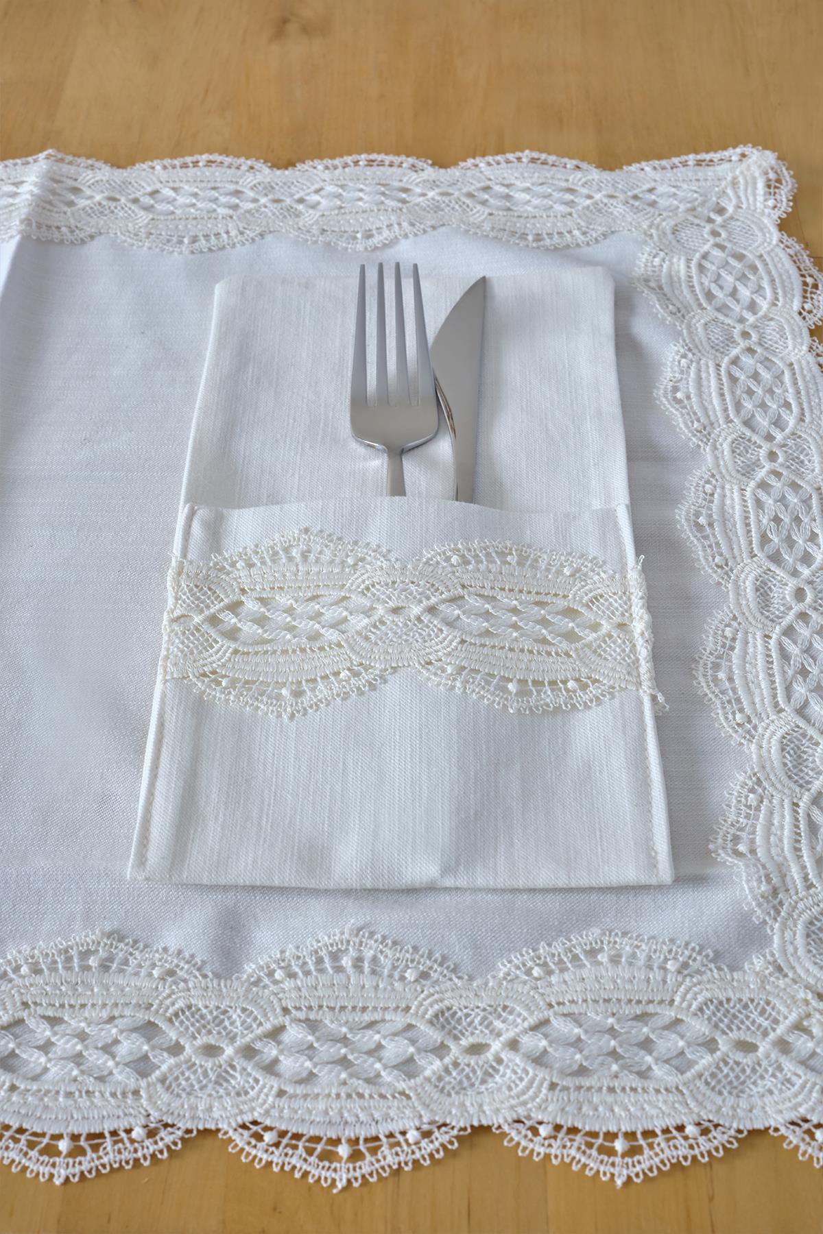 Set de servilletero elegante con tenedor y cuchillo sobre un mantel blanco con borde de encaje