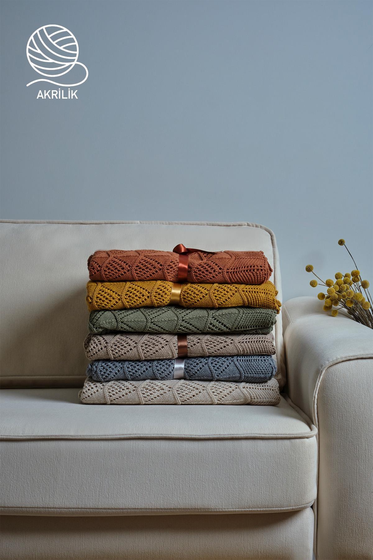 Mantas de punto acrílico apiladas sobre un sofá, en varios colores, decoración moderna
