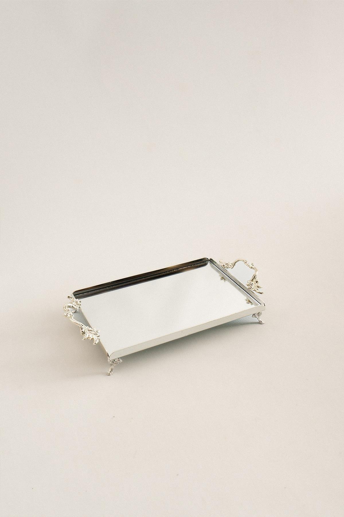Bandeja pequeña de plata rectangular con asas elegantes, superficie de espejo y detalles de patas talladas.