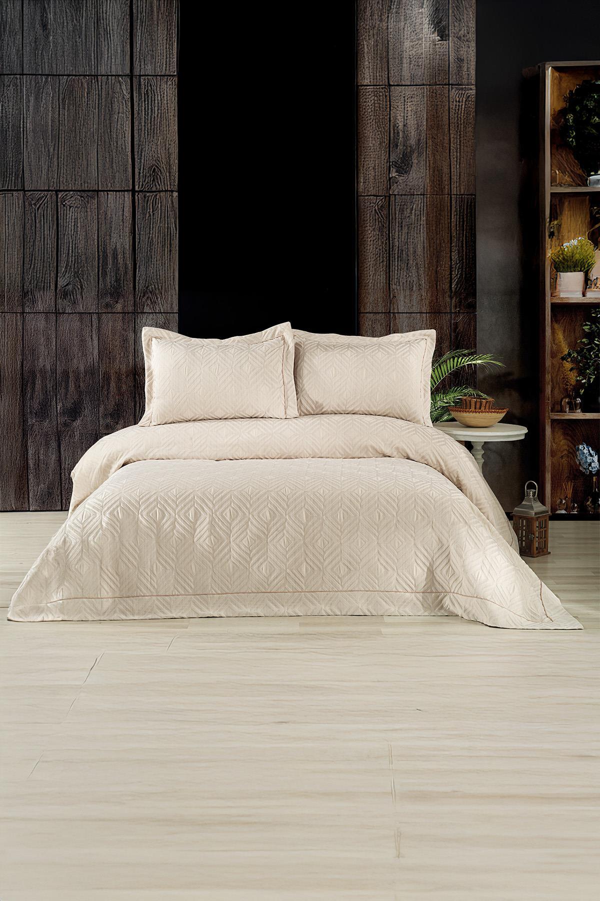 Colcha doble de jacquard con patrón geométrico en color beige y almohadas, en un dormitorio moderno.