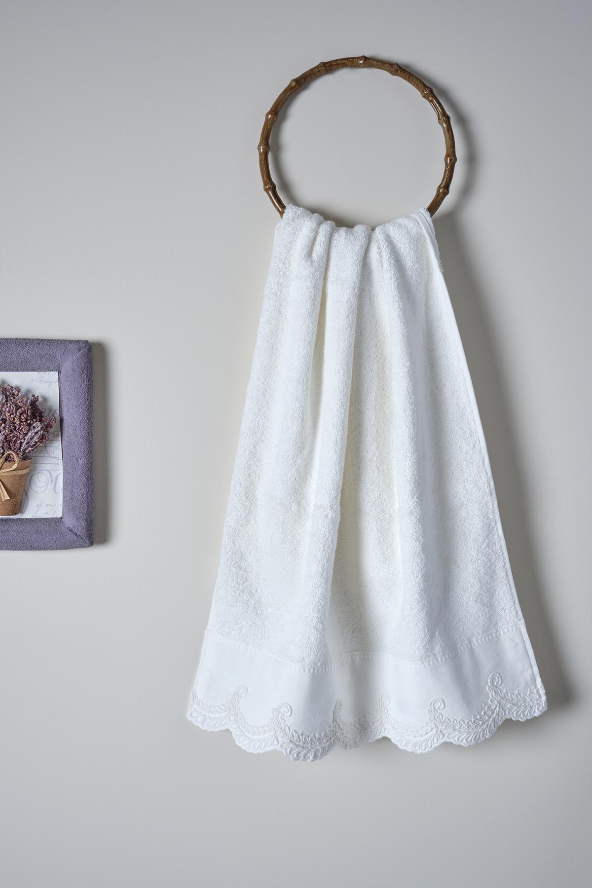 Toalla de cara blanca de 50x90 cm con detalles bordados, colgada.