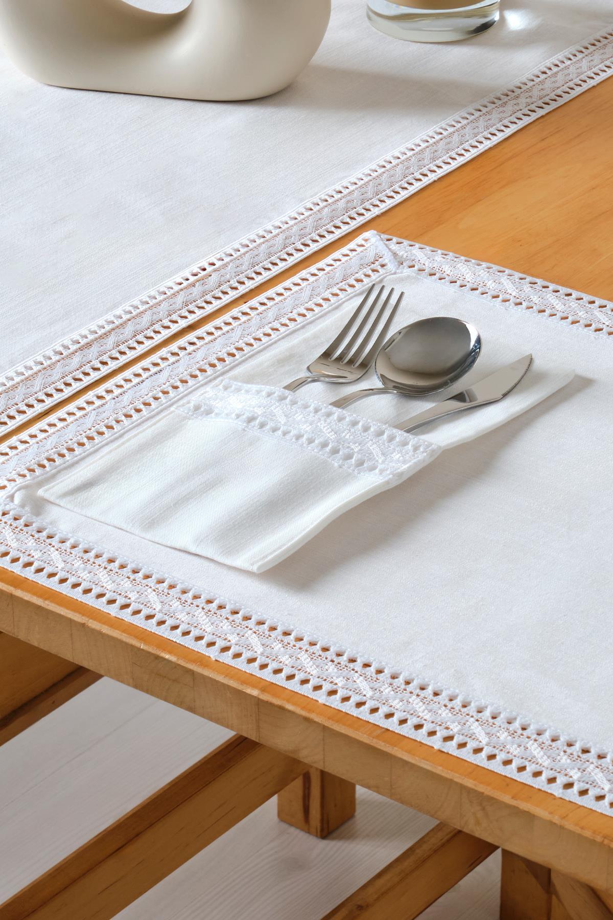 Decoración de mesa elegante con mantel blanco de encaje y cubiertos (tenedor, cuchillo y cuchara) en un bolsillo.