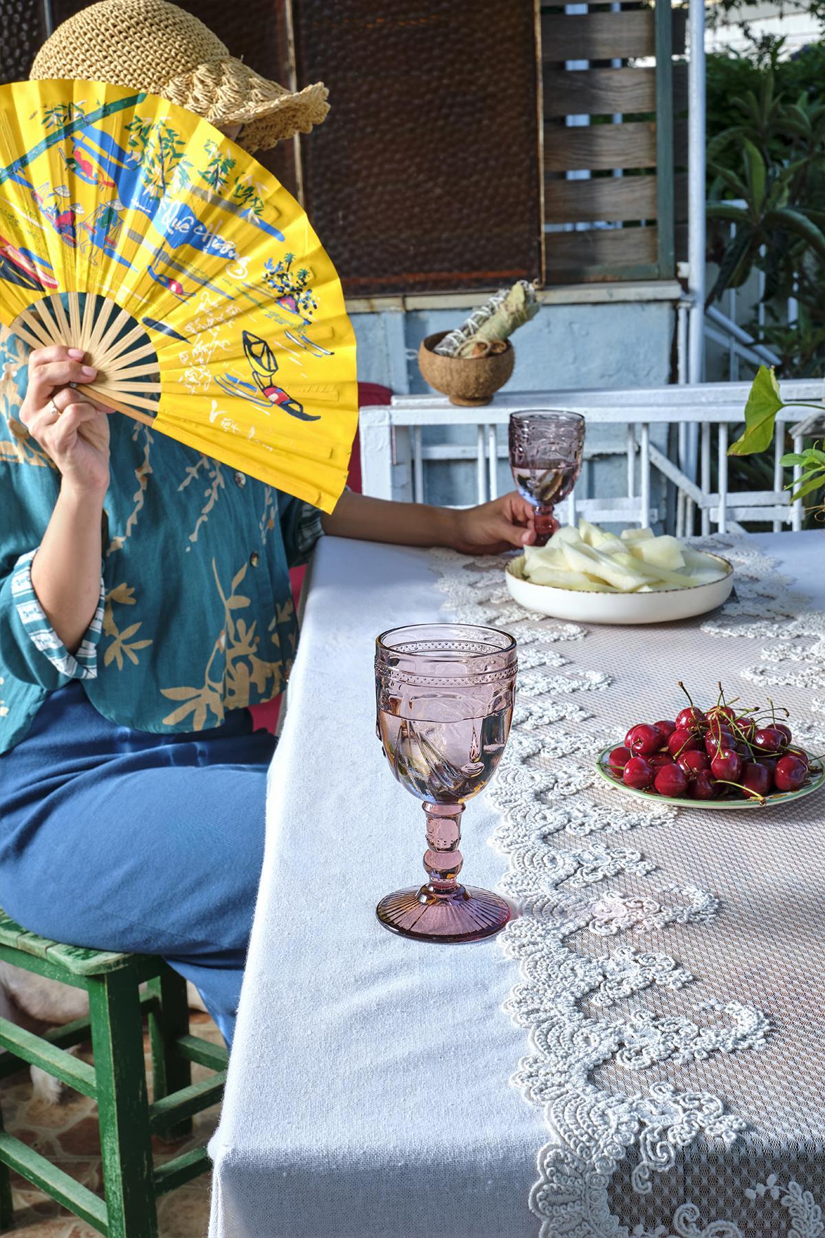 Mantel de encaje con una mesa al aire libre decorada con cerezas y vasos elegantes