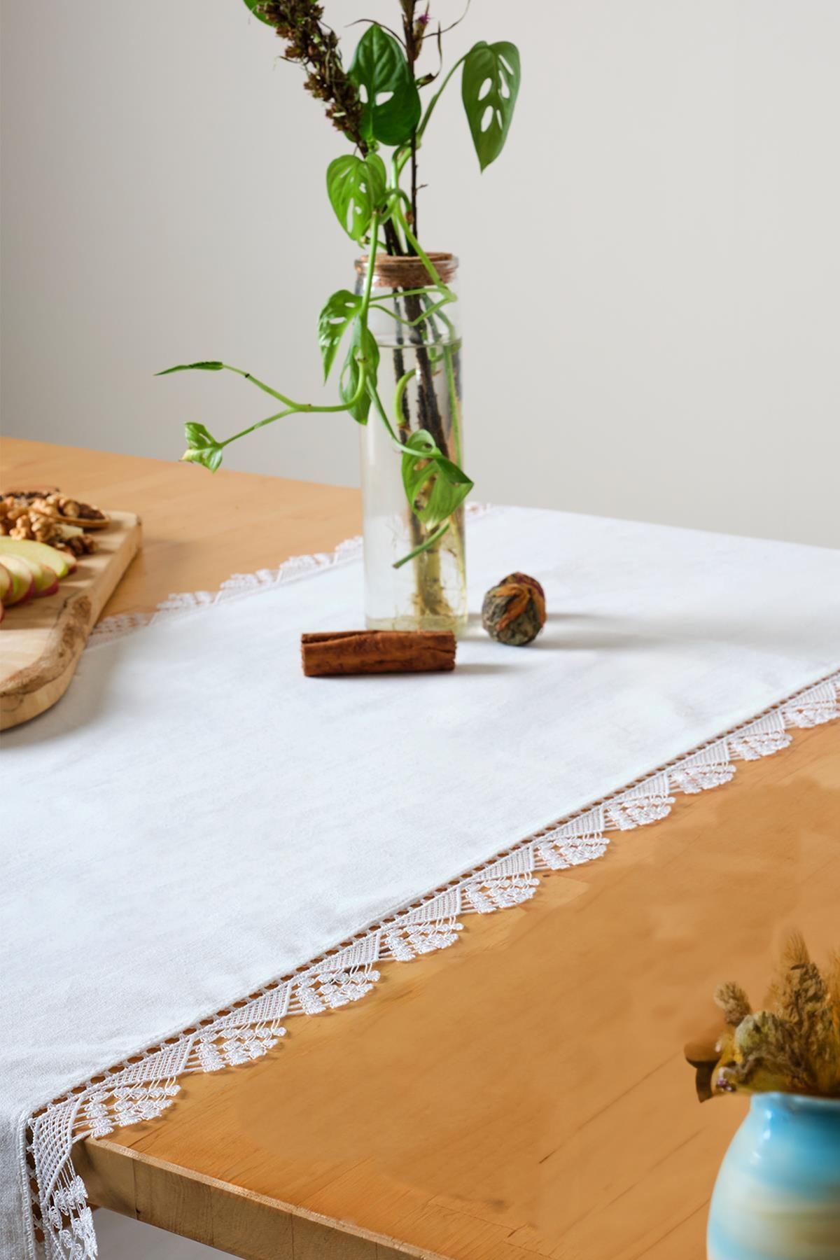 Camino de mesa blanco con encaje, con un aspecto decorativo elegante y sofisticado sobre una mesa de madera.